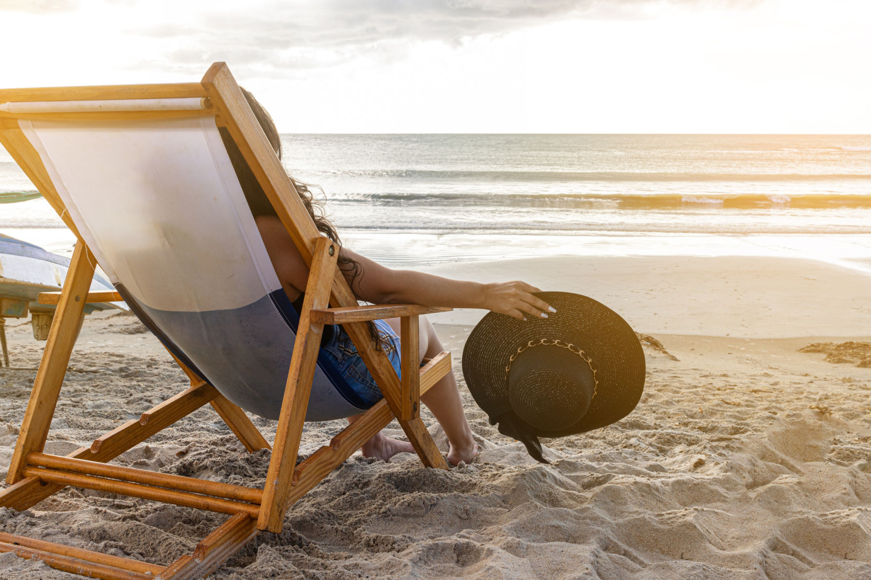 Woman sitting in a beach chair holding her hat